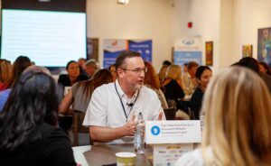 HDMS22-85 Roundtable Greg Jenn Edits People around a table at a conference talking